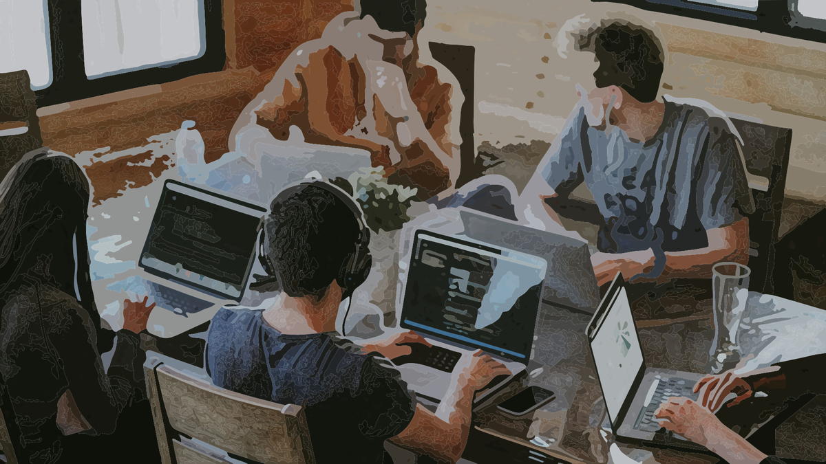 A group of people in their 20s or 30s working on laptops around a table.